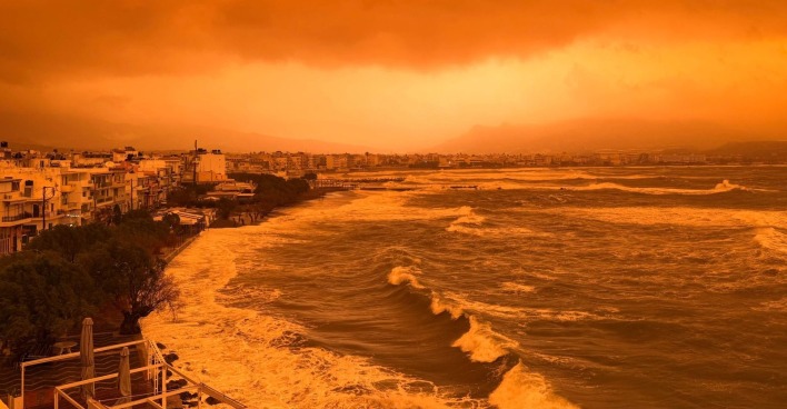 Saharastaub über Kreta färbt Himmel orange, starke Wellen an Küste, schlechte Sicht durch Feinstaubbelastung im Mittelmeerraum.