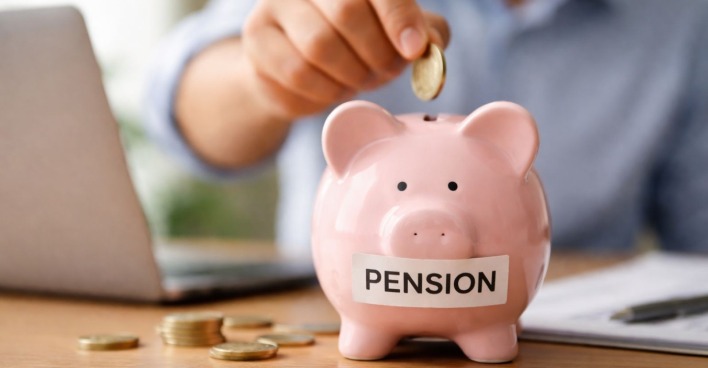 Symbolbild für Zusatzpension in Österreich: Eine Person legt Geld in ein Sparschwein, während sie ihre Altersvorsorge am Laptop organisiert.