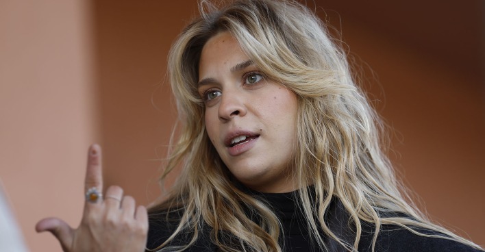 Anja Windl alias „Klima-Shakira“ spricht vor Gericht und gestikuliert mit der Hand. Die Klima-Aktivistin trägt ihre langen blonden Haare offen und blickt ernst in die Kamera.