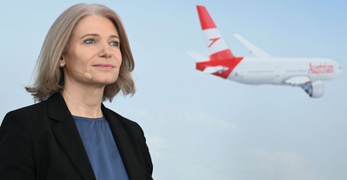 Frau spricht auf einer Pressekonferenz, dahinter ist ein Flieger zu sehen