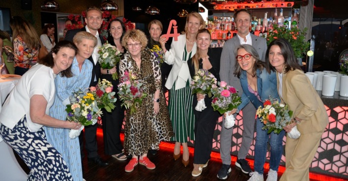 Mehrere Personen halten Blumensträuße in den Händen und lächeln in die Kamera