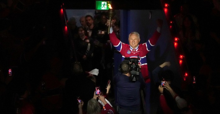 Der ehemalige Eishockey-Profi Claude Lemieux hebt lächelnd die Hände auf dem Eis bei einer Ehrung