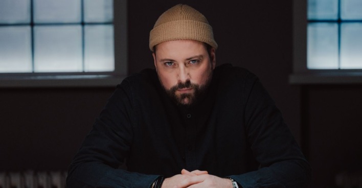Schauspieler Felix von Jascheroff blickt als John Bachmann nachdenklich durch die Kulissen des GZSZ-Kiez