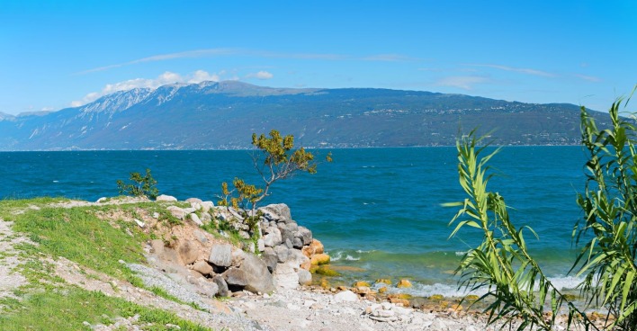 Gardasee mit klarem Wasser und Bergen im Hintergrund während seltener vollständiger Durchmischung des Sees