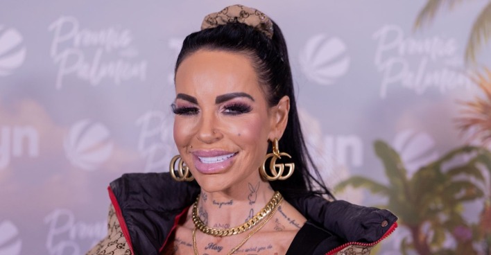 Gina-Lisa Lohfink bei einem öffentlichen Event mit schwarzen Haaren, auffälligem Make-up und goldenen Accessoires. Die Reality-TV-Bekanntheit sorgt aktuell wegen ihrer schweren Gesundheitskrise für Schlagzeilen.