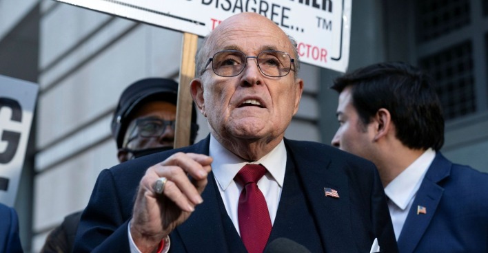 Rudy Giuliani spricht bei einem öffentlichen Auftritt mit Mikrofon und roter Krawatte in New York