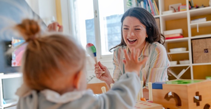 Eine Frau betreut ein kleines Mädchen in einem Kinderzimmer.