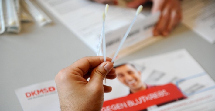 Mensch hält zwei lange Wattestäbchen in der Hand