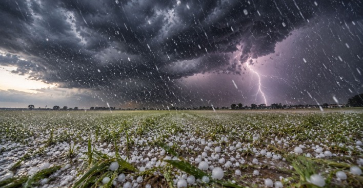 Hagelkörner rauf einem Feld und Gewitterwolken