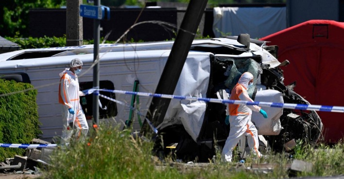 Zugunfall Belgien Schulbus: zerstörter Kleinbus nach Kollision mit Zug am Bahnübergang in Buggenhout mit Einsatzkräften vor Ort