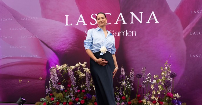 Amira Aly steht lächelnd und mit rundem Babybauch auf einem violetten Teppich auf der Lascana-Gala in Hamburg