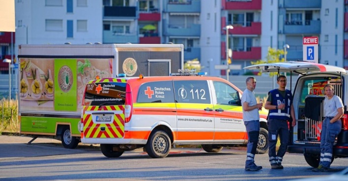 Ermittler stehen mit Rettungswägen vor Wohnhäusern