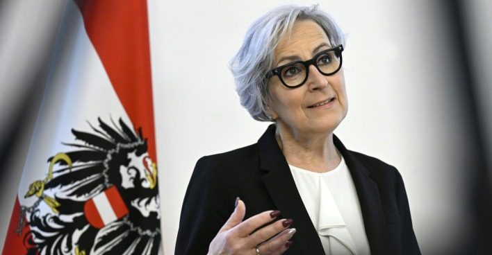 Eine Frau im Anzug und mit Brille gestikuliert mit ihrer Hand
