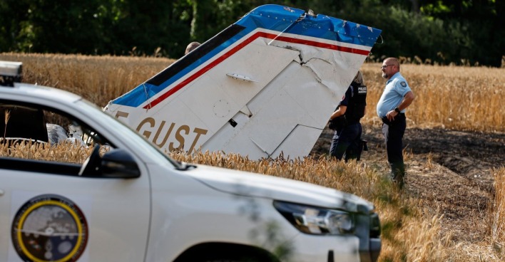 Flugzeugteile liegen am Boden, davor steht ein Polizeiauto