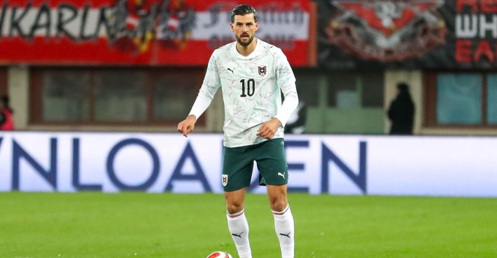 Ein Mann steht in Sportmontur am Fußballfeld