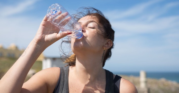 Frau trinkt Wasser während der Hitzewelle in Österreich, um sich bei extremer Hitze und Temperaturen bis zu 40 Grad abzukühlen.