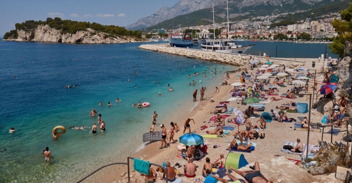 Hitzewelle Kroatien: Überfüllter Strand an der Adria bei hohen Temperaturen und Badenden im Meer