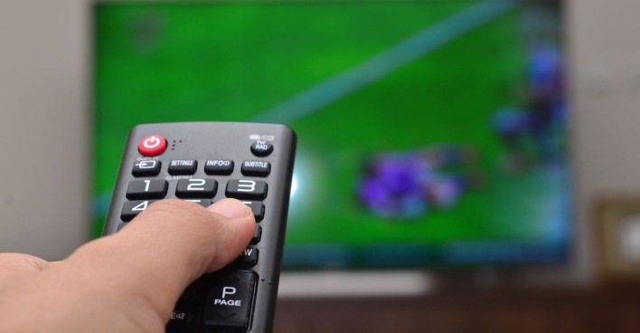 TV-Fernbedienung vor einem Fernseher eines Fußballspiels als Themenbild für die Live-Übertragung des WM-Spiels Österreich vs. Jordanien im ORF
