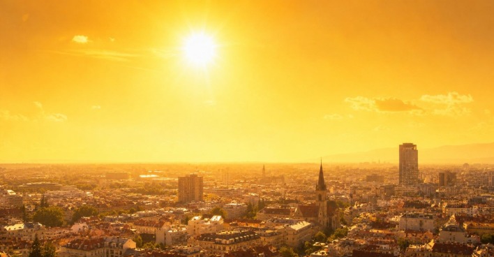 Stadtansicht unter intensiver Sonneneinstrahlung mit grellem Himmel und Hitze flimmernder Luft, Symbolbild für extreme Hitze und Hitzewelle in Europa aufgrund der Omega-Lage