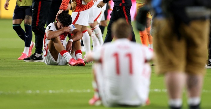 Mehrere Fußballspieler sitzen auf dem Rasen