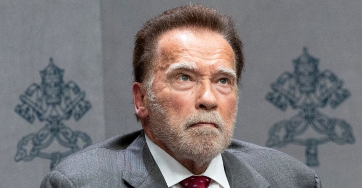 Arnold Schwarzenegger bei einem öffentlichen Auftritt kurz vor seinem 79. Geburtstag im grauen Anzug und mit ernstem Blick.