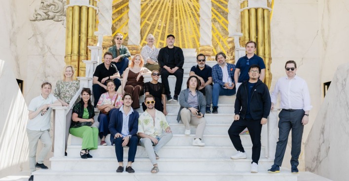 Schauspieler und Opern-Produzenten sitzen auf einer weißen Treppe in den Bühnenkulissen