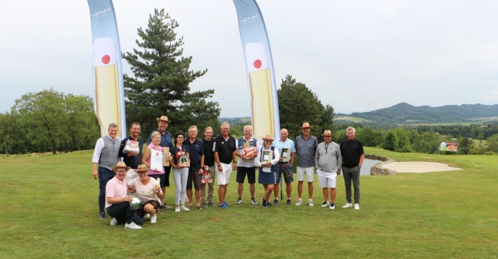 Gruppenfoto der Teilnehmerinnen und Teilnehmer eines Golfturniers mit Siegern und Organisatoren auf dem Golfplatz vor der Siegerehrung.