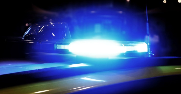 Ein Einsatzfahrzeug der Polizei steht mit Blaulicht vor einem Gebäude