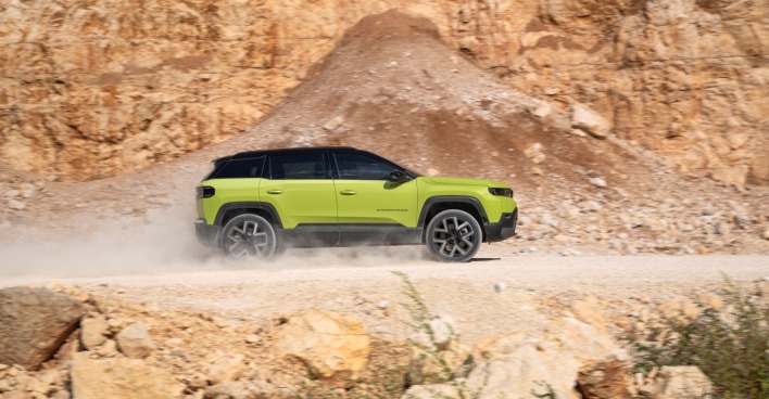 Ein zitronengelber Jeep Compass fährt auf eine staubigen Straße, vermutlich in einen Steinbruch.