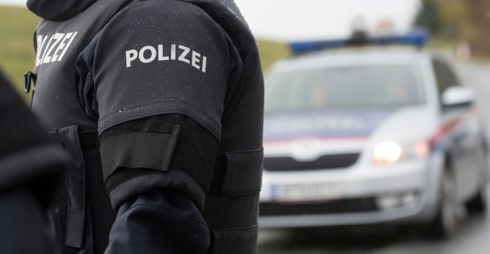 Polizist vor Einsatzfahrzeug bei Ermittlungen nach Mordversuch in Kufstein mit Gabel-Attacke