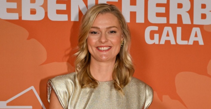 Miriam Höller lächelt bei einem öffentlichen Event in einem goldenen Kleid. Die ehemalige Stuntfrau spricht zehn Jahre nach ihrem Schicksalsjahr über Verlust, Neuanfang und ihr neues Glück.