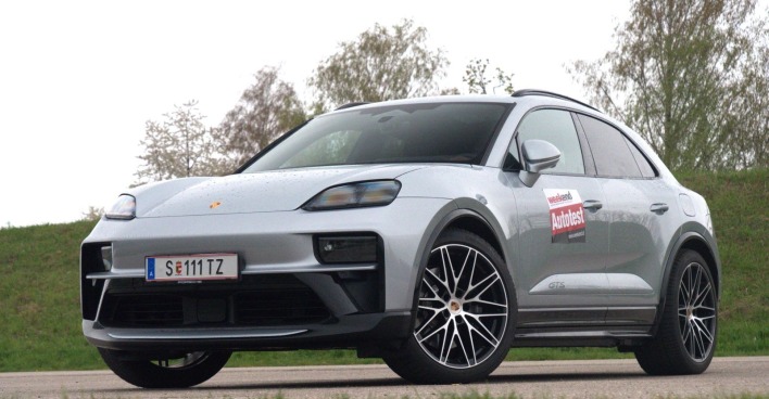 Ein silberner Porsche Macan GTS parkt vor einer Böschung. Im Hintergrund sind einige Laubbäume zu sehen.
