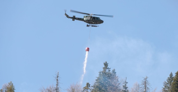 Hubschrauber löscht Waldbrand Tirol bei Wildermieming mit Löschwasser aus der Luft