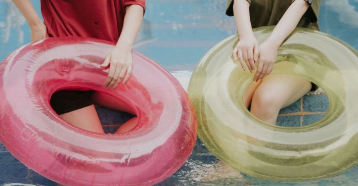 Wasserrutsche Wien: Zwei Personen sitzen mit aufblasbaren Schwimmringen am Wasser. Das Symbolbild steht für den Sommer-Spaß rund um die 75 Meter lange Wasserrutsche mitten in Wien.