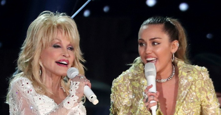 Dolly Parton und Miley Cyrus singen gemeinsam mit Mikrofonen auf einer Bühne.