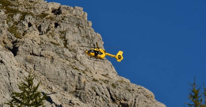 Ein gelber Rettungshubschrauber bei einem Einsatz in den Bergen.