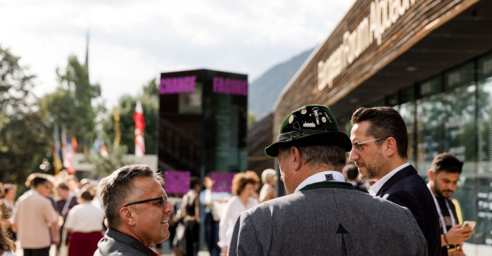 Gruppe von Männern stehen vor einer Veranstaltungshalle beim European Forum Alpach