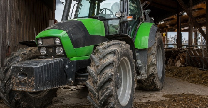 Grüner Traktor in einem Kuhstall als Symbolbild für den tödlichen Traktor-Unfall in Höchst in Vorarlberg.