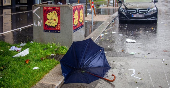 Unwetterwarnung Wien: Umgestürzter Regenschirm auf nasser Straße bei starkem Regen und Sturm in Wien.