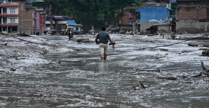 Mann geht durch Schlamm und Geröll nach der verheerenden Sturzflut in Nepal.