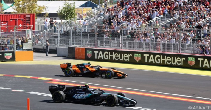 Formel-1-Boliden von Mercedes und McLaren auf dem Stadtkurs vor einer voll besetzten Tribüne.