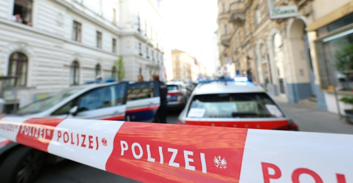 Mehrere Polizeiautos und ein Absperrband vor einer Wohnung