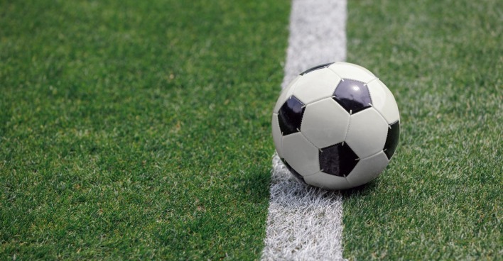 Ein Fußball liegt auf dem Spielfeld eines leeren Stadions