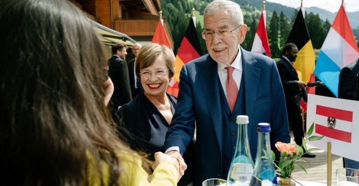 Bundespräsident und seine Gattin begrüßen Gäste vor einer Tiroler Berglandschaft