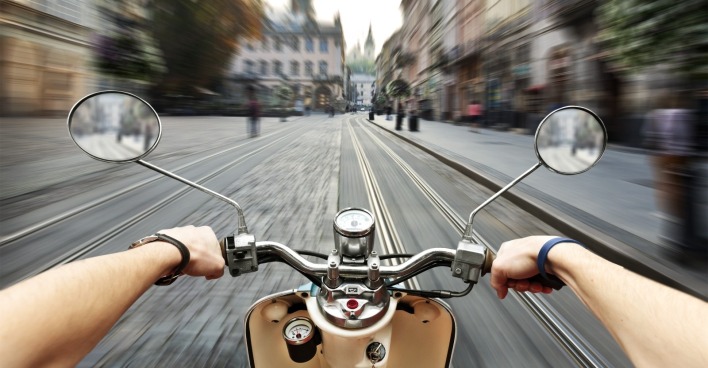 Mann, der auf dem Roller in alten Straßen der Stadt fährt.