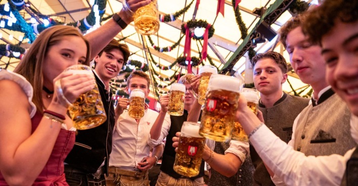 Junge Menschen feiern mit Bier auf dem Oktoberfest in München.
