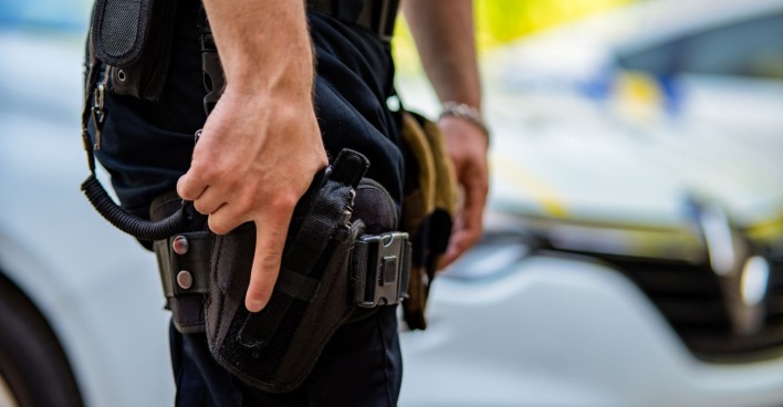 Ein Polizist zückt seine Dienstwaffe.