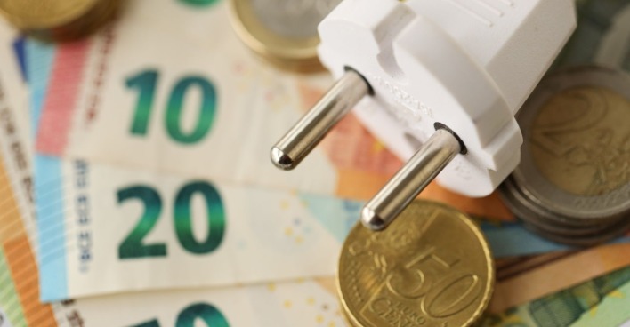 Stromstecker auf Euro-Scheinen und Münzen als Symbol für den neuen Strompreisdeckel in Österreich.