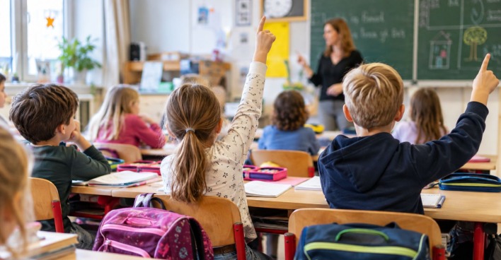 Kinder sitzen im Unterricht einer Volksschule und melden sich. Ab 2027 startet ein Schulversuch mit sechsjähriger Volksschule.