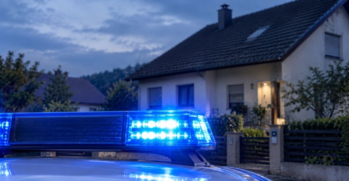 Eingeschaltete Sirene eines österreichischen Polizeiwagens vor einem Haus
